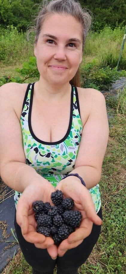 Sunny holding a handful of freshly picked Midnight Jewel blackberries